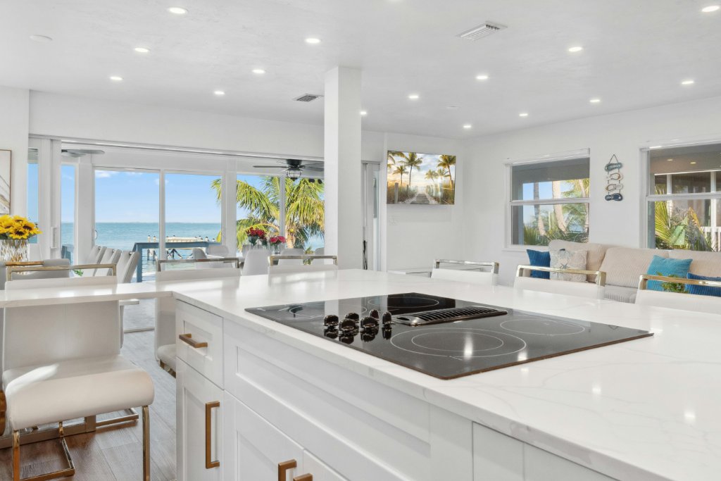 An open kitchen and living room looking through glass doors to the ocean