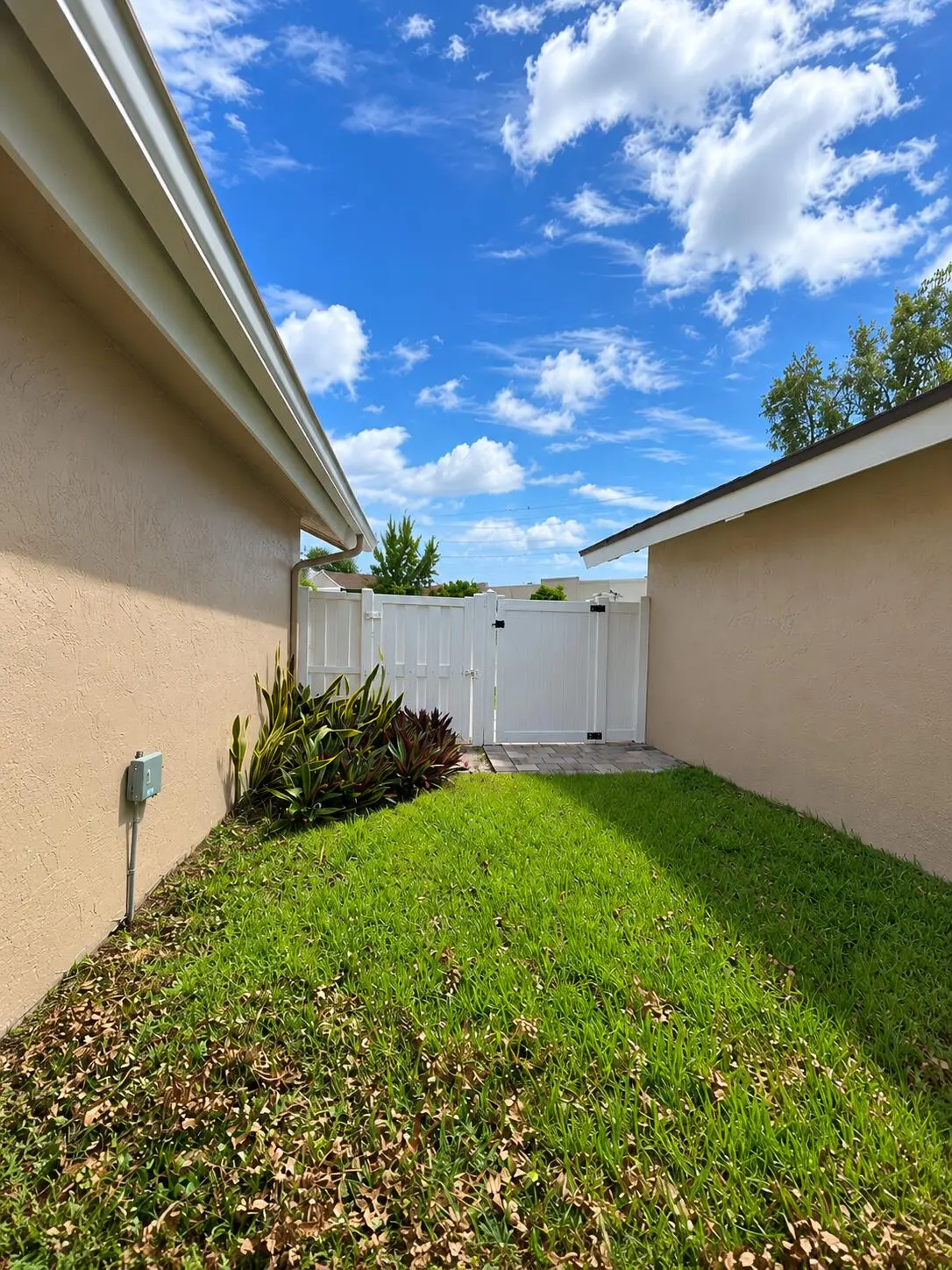 Sunny Stucco Side Yard with White Gate at 1238 NW 51ST Way 1238, Deerfield Beach