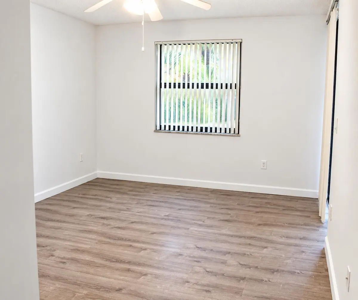 Bright Empty Room with Vertical Blinds at 4450 NW 30TH Street 111, Coconut Creek